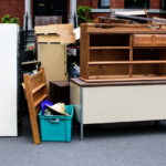 Items and old furniture on street outside house moving day or getting rid of junk concept